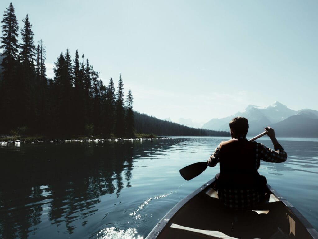 man on canoe sailing on the river